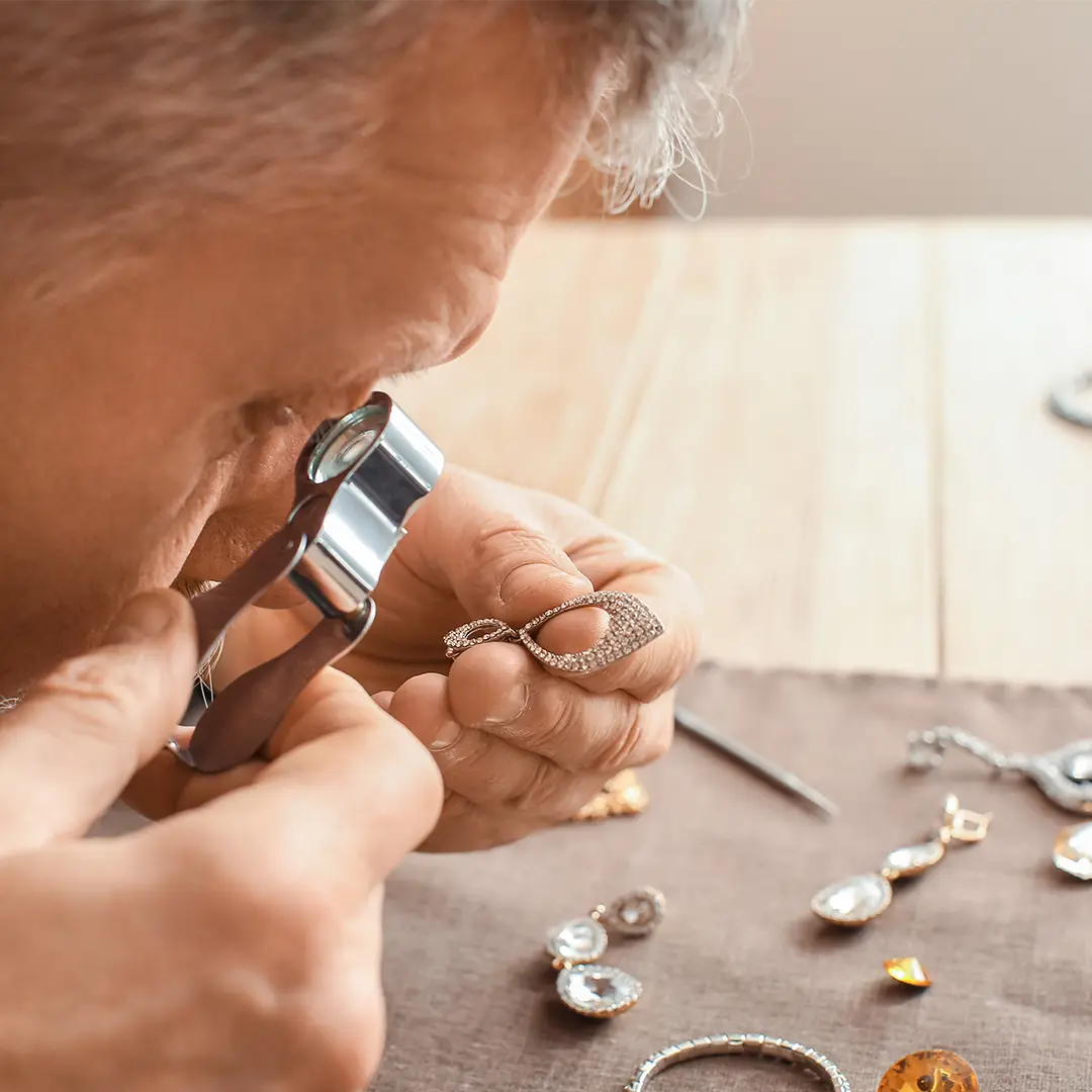 Expert en joaillerie examinant une bague à la loupe pour établir la valeur assurée des bijoux